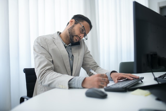 person sitting at their desk talking on the phone and taking notes